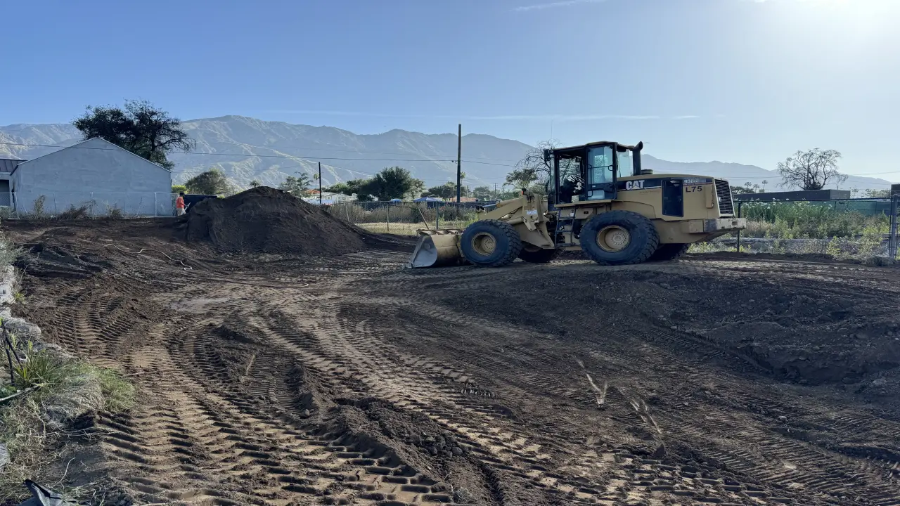 Construction site with CAT loader on Altadena hillside, grading and drainage work in progress